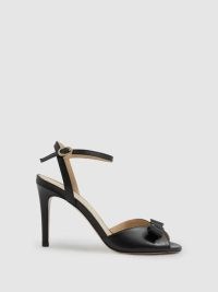 Camilla Elphick Aubrey Leather Open-Toe Heels in Black – high heel bow embellished ankle strap sandals