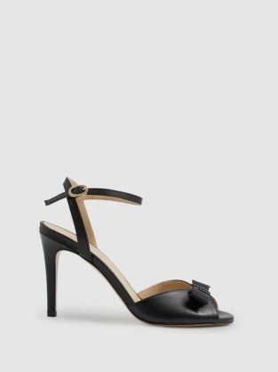 Camilla Elphick Aubrey Leather Open-Toe Heels in Black – high heel bow embellished ankle strap sandals